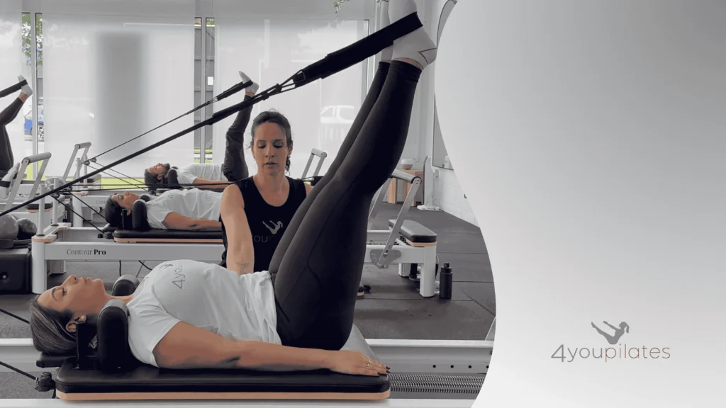 Pilates instructor guiding a client through reformer leg exercises with straps in the 4You Pilates studio.”