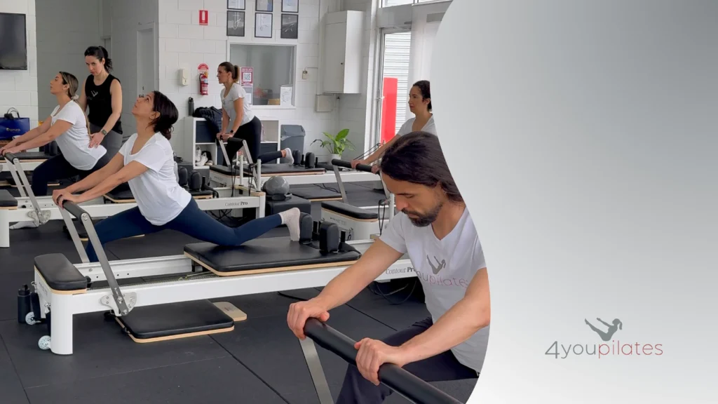 People practicing reformer Pilates lunges in a small group class inside the studio.
